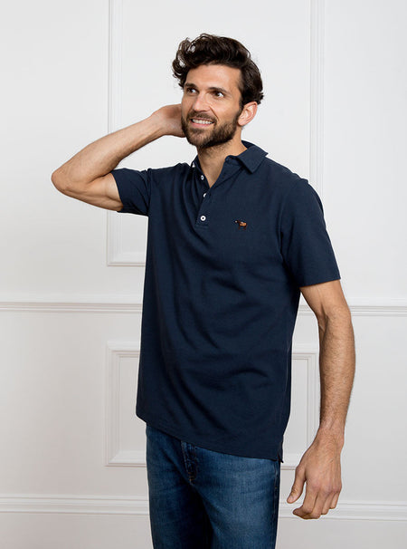 Man wearing navy blue polo shirt in 100% cotton with Newmarket 875 horse logo embroidered on the front.